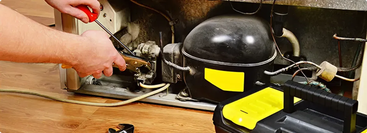 Refrigerator repair technician fixing the compressor and wiring in Perrysburg, OH
