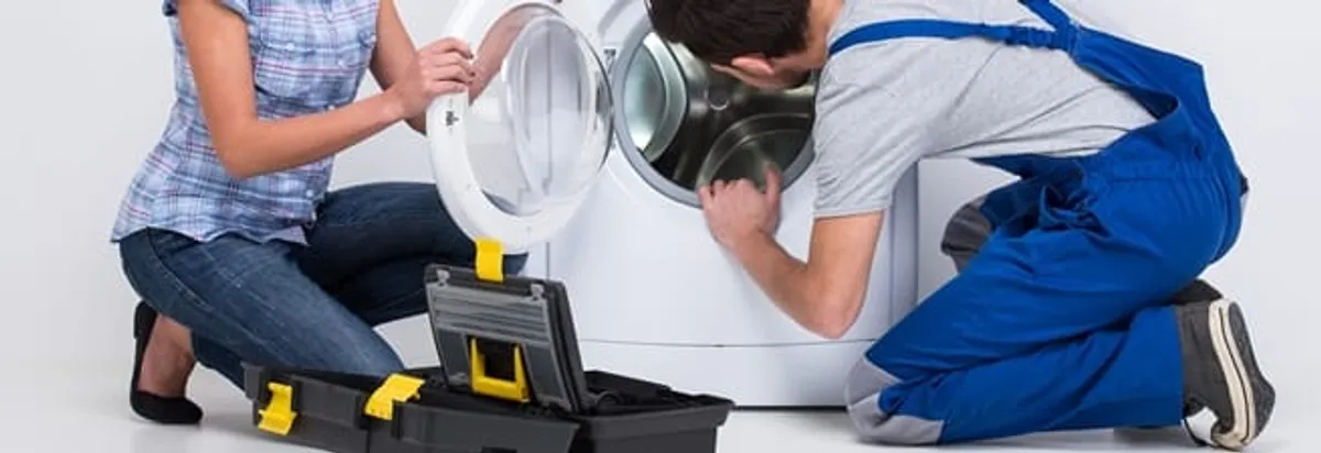 Washer repair technician inspecting a front-load washing machine with tools in Toledo, OH