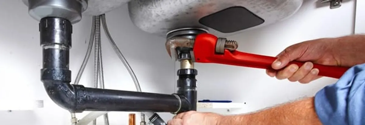 Garbage disposal repair technician tightening the sink drain and disposal connection in Toledo, OH