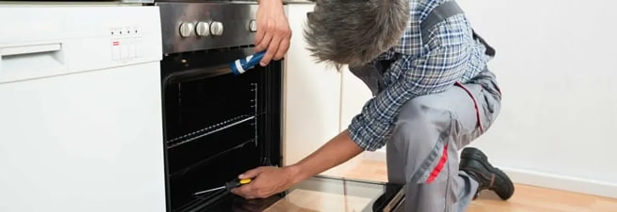 Oven repair technician inspecting and servicing an electric oven in Toledo, OH