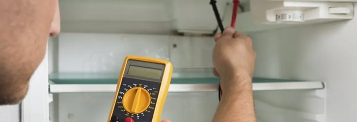Refrigerator repair technician testing electrical components with a multimeter in Toledo, OH