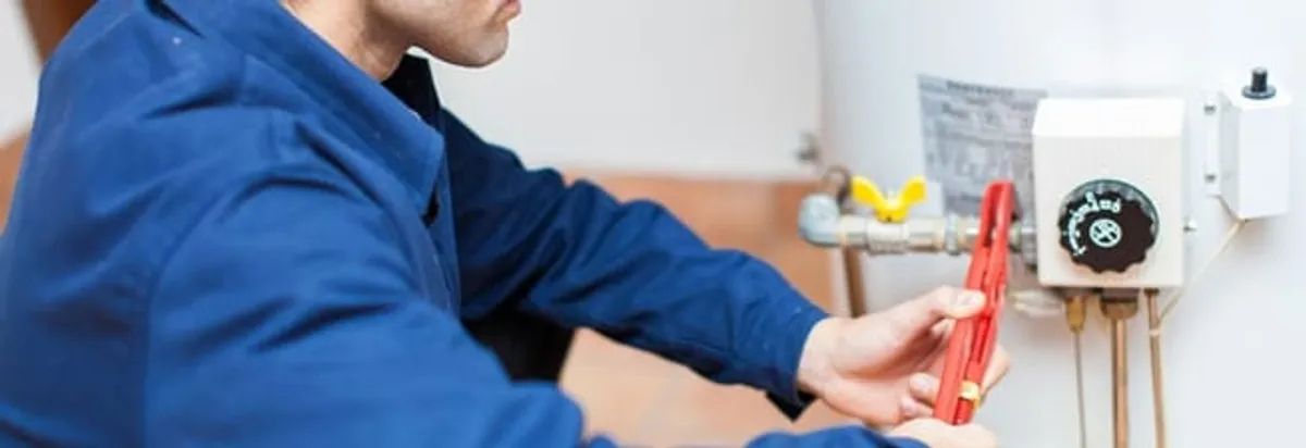 Water heater repair technician adjusting the temperature control and gas valve in Toledo, OH